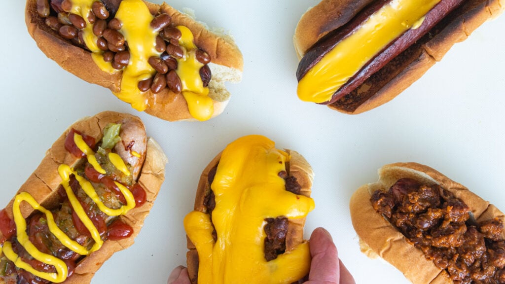 Hand reaching for loaded hot dog.