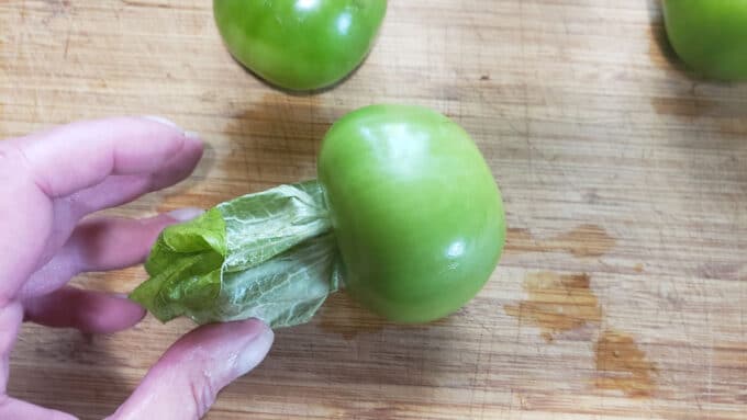 Grabbing husk between fingers to remove.