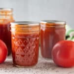Many jars of tomato ketchup with fresh tomatoes