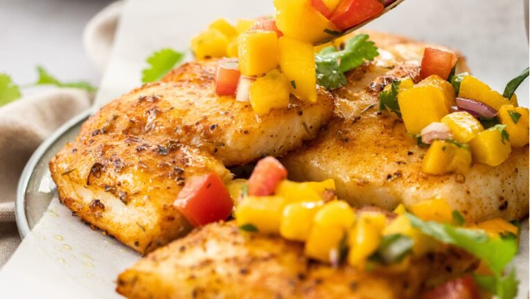 Big chunks of mahi mahi served on a plate with a colorful salsa.