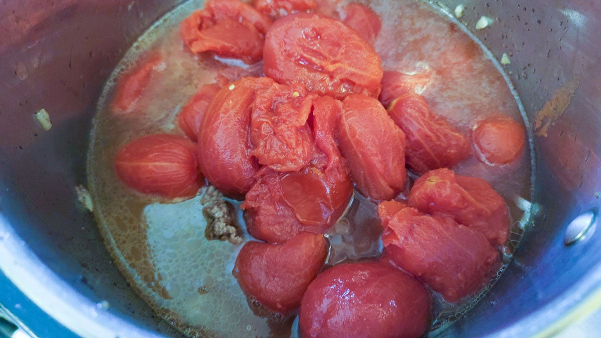 Tomatoes added to the meat in the pan.