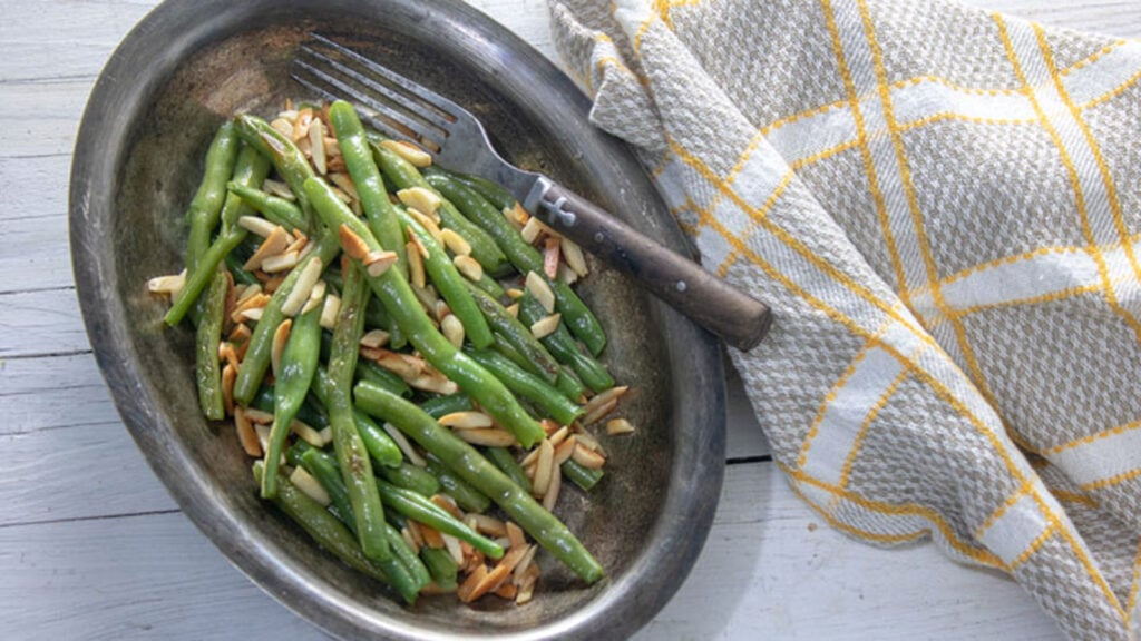 Green beans and almonds, toasted, in silver platter.