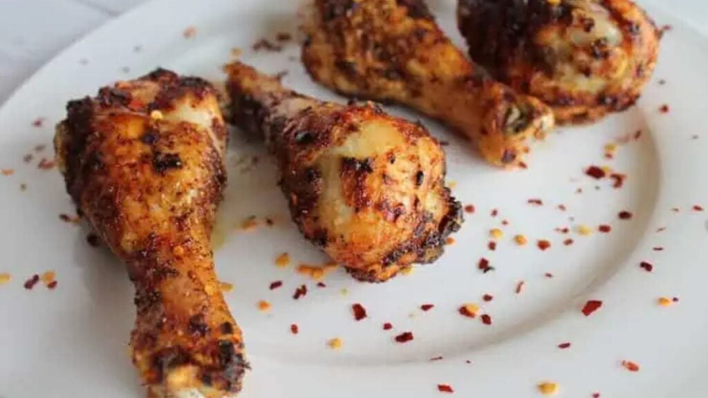 Chicken drumsticks on a plate with chili flakes.