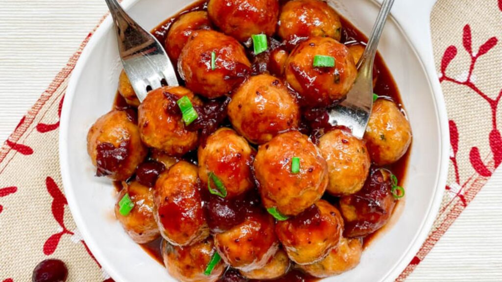Meatballs on a plate with utensils on the side.