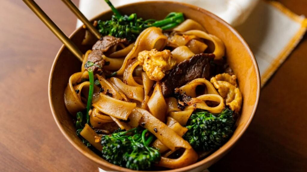 Noodles with in a bowl with chopsticks on the side.