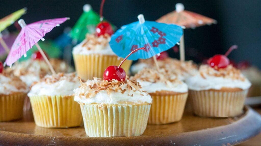 Pina colada cupcakes with cherries on top.