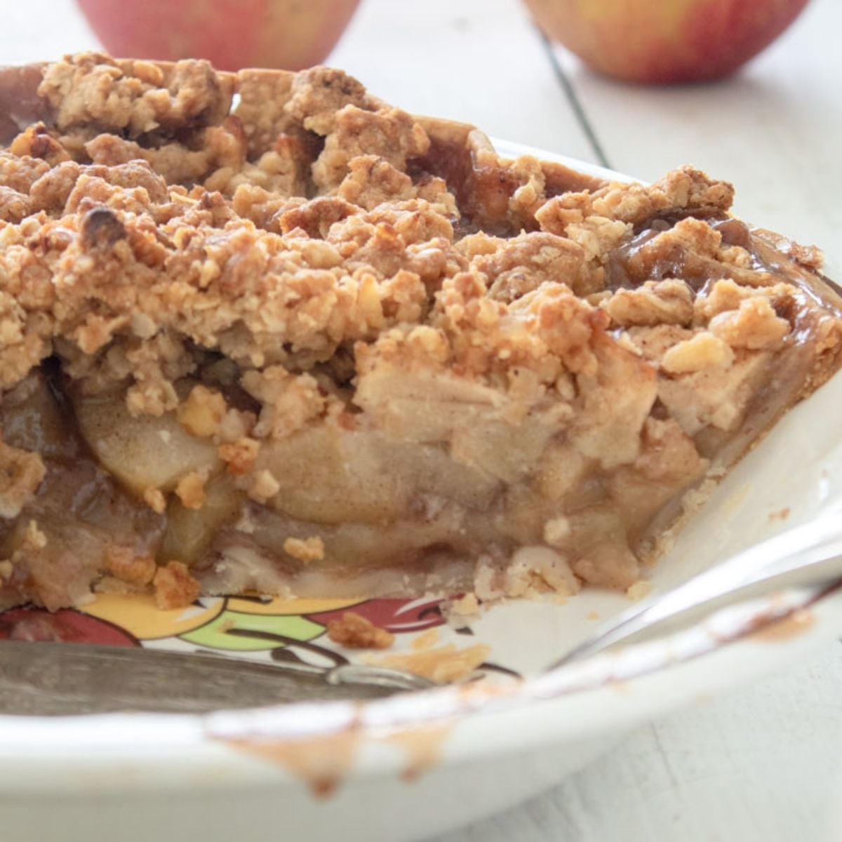 Closeup image of a cut apple crumb pie in a pie plate.