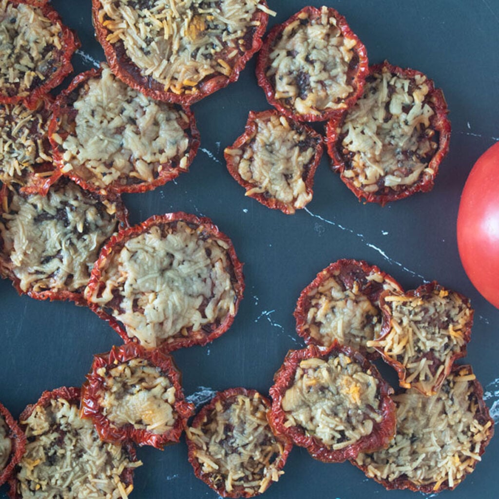 Parmesan tomato chips on a black board.