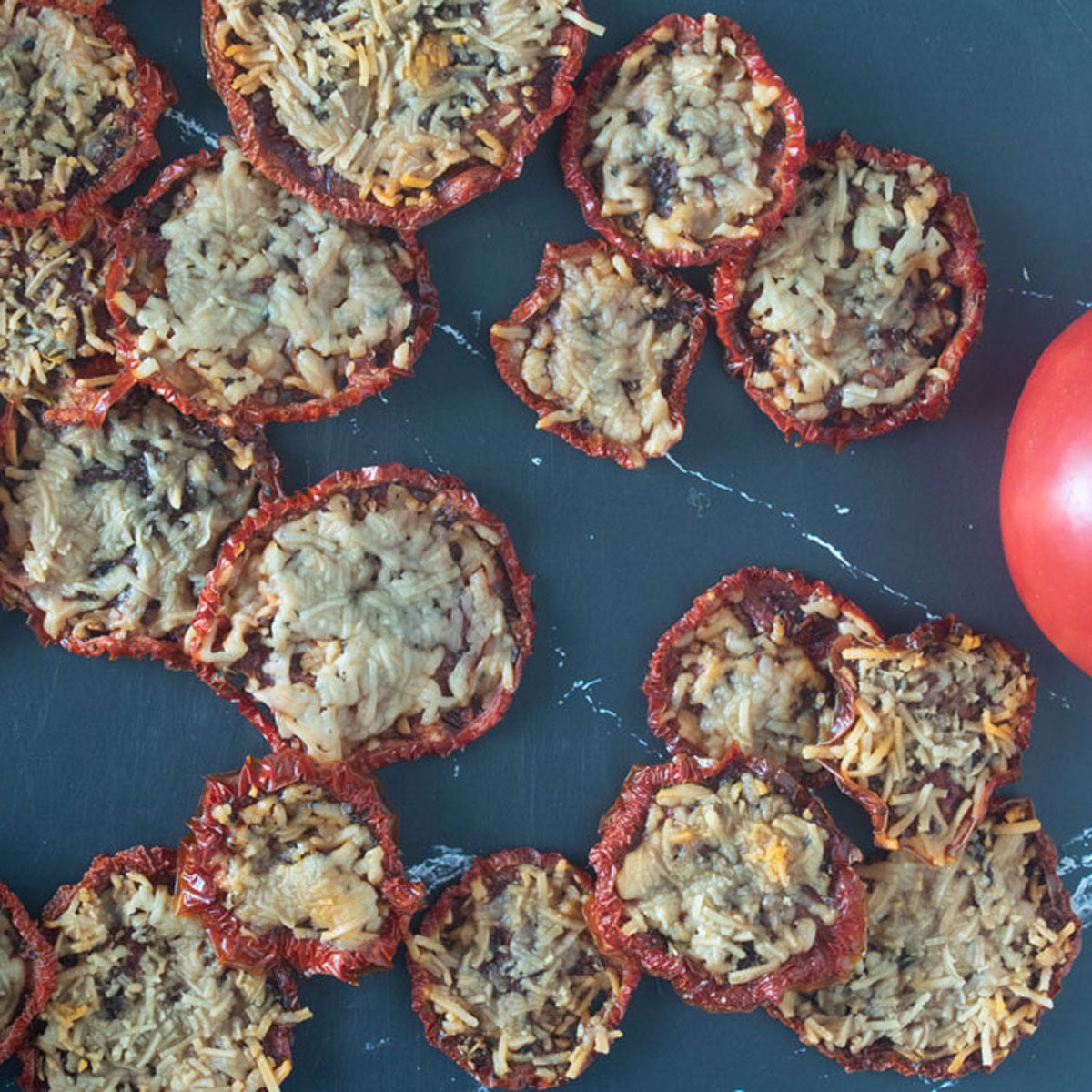 Parmesan tomato chips on a black board.