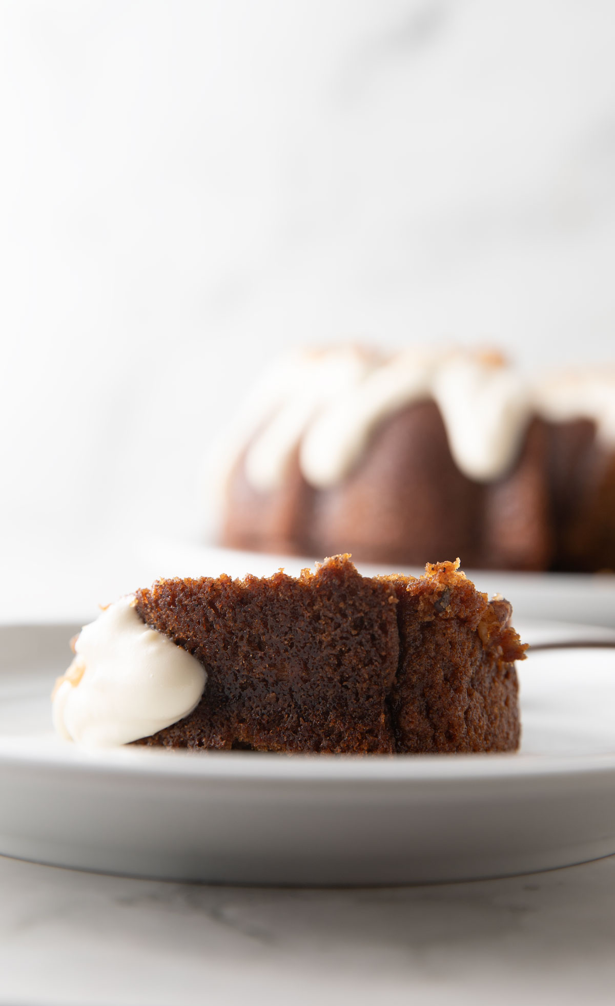 Butternut squash cake with cream cheese icing slice on a white plate.