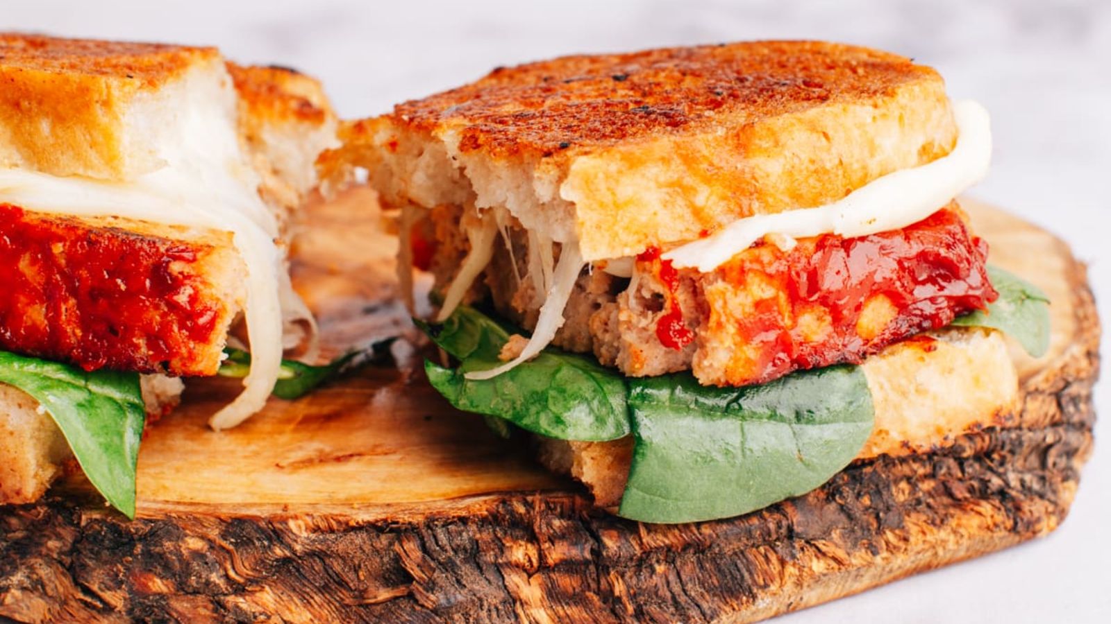 A slice of meatloaf sandwich on a wooden board.