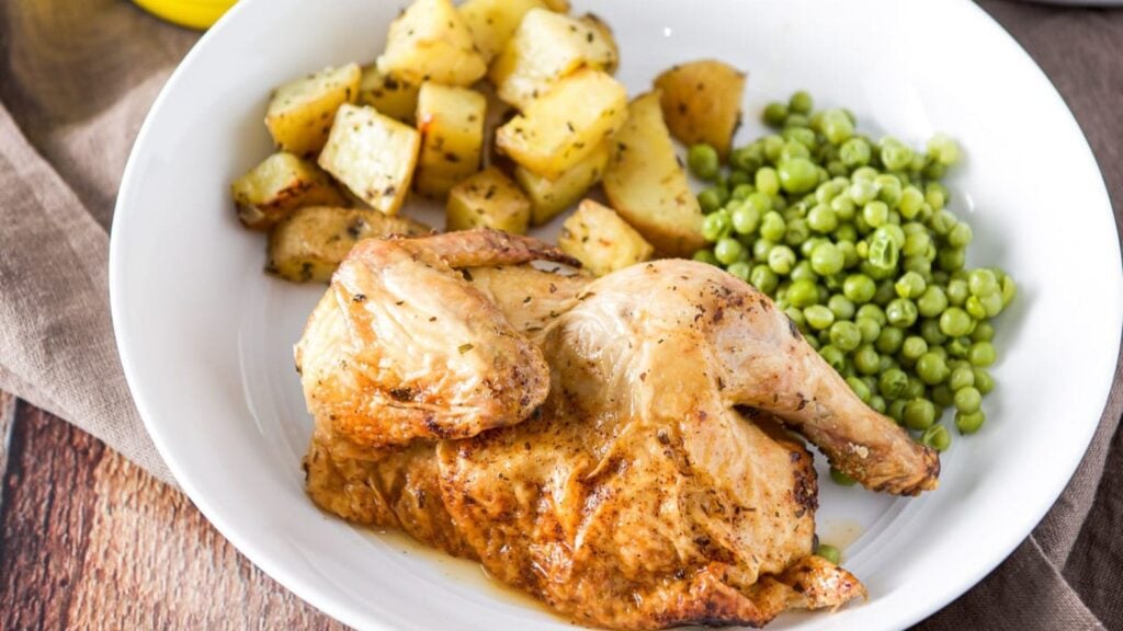 Cornish hen with green peas and potatoes on the side.