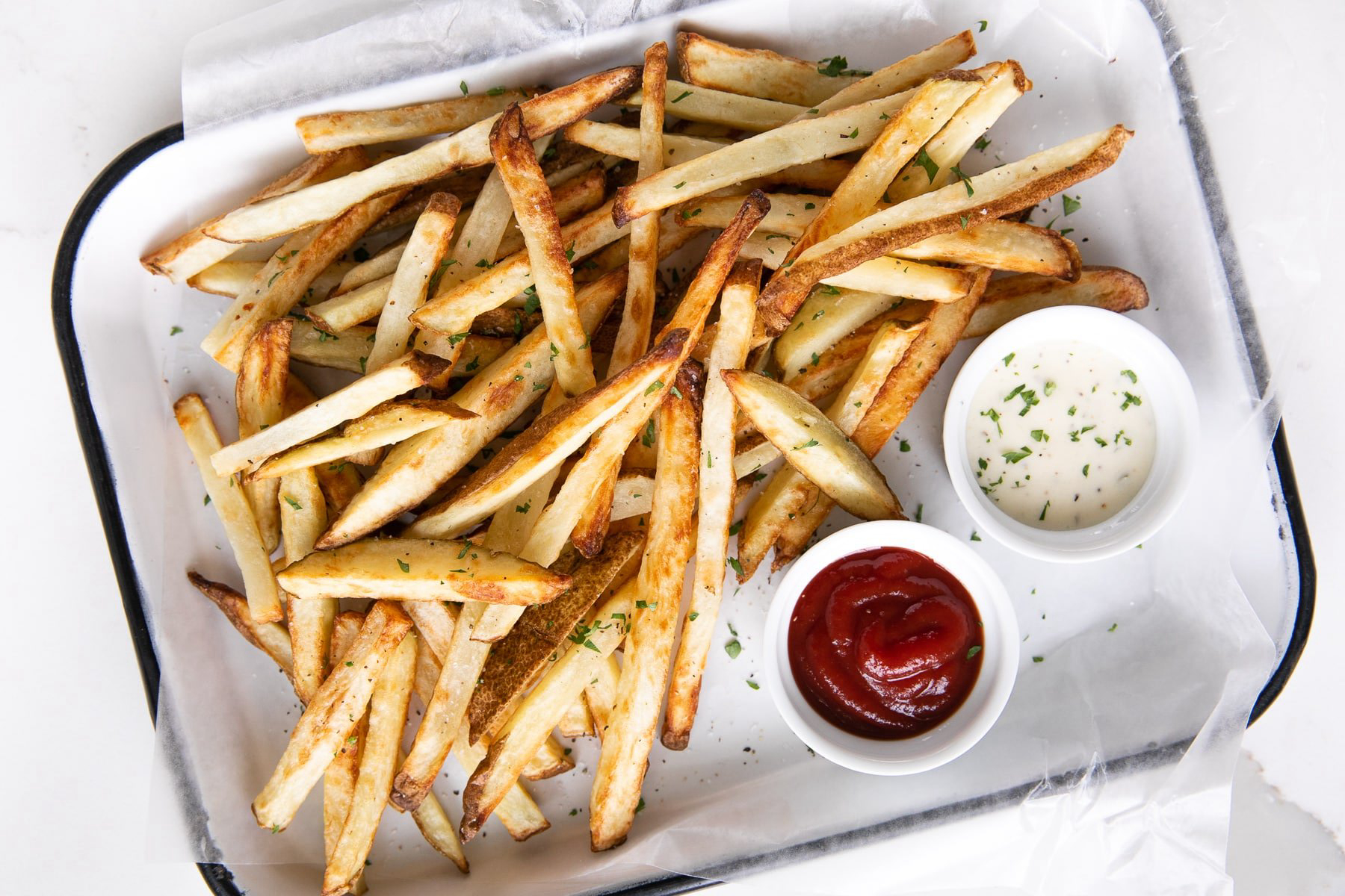 French fries on a white baking dish with bowls of sauces.