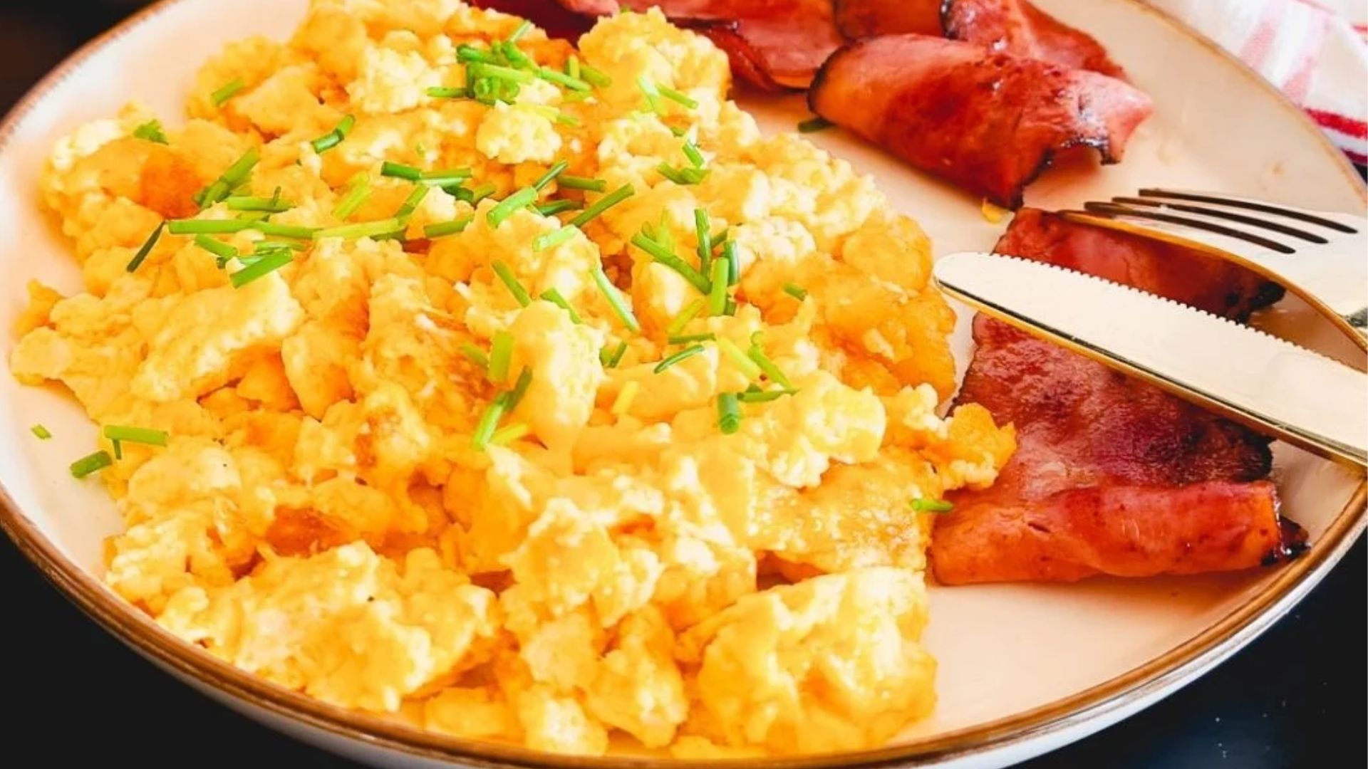 Scrambled egg and bacon on a plate.