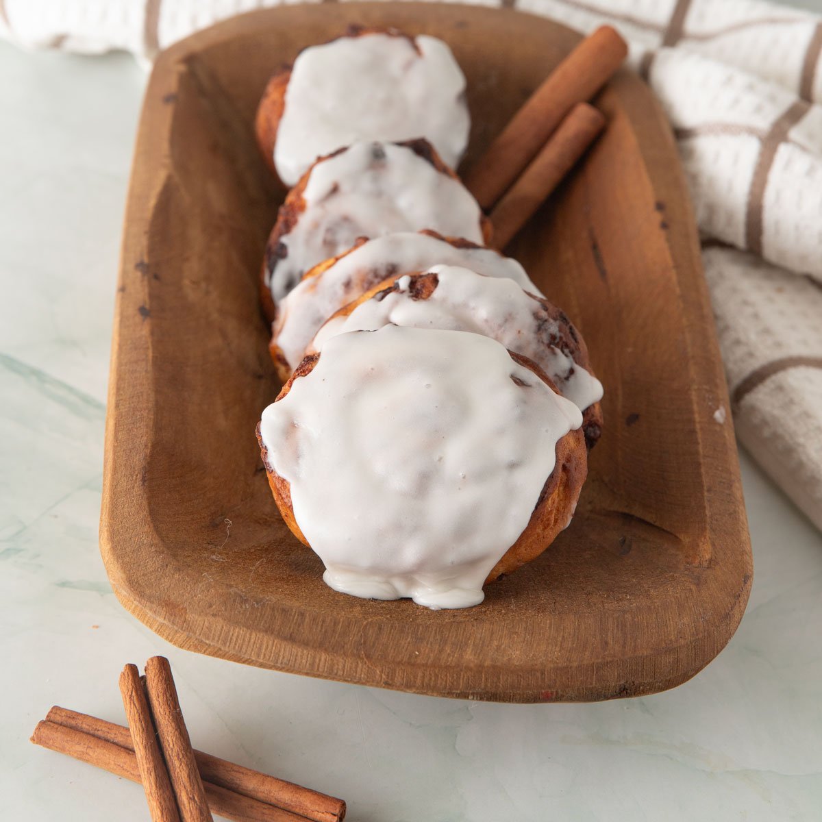 Row of cinnamon rolls in a wooden bowl.