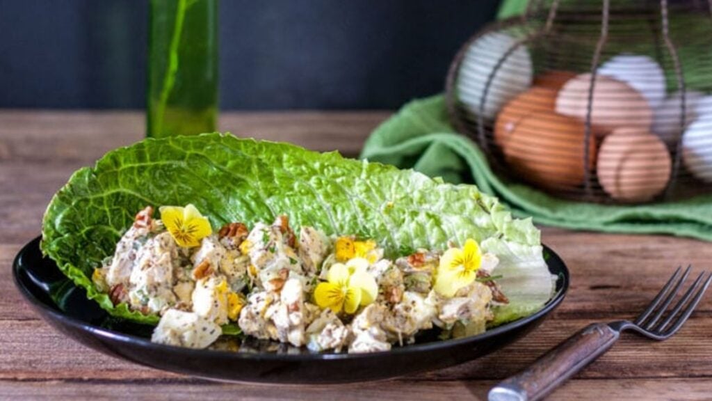 Grilled chicken salad with eggs and pecans in a plate.