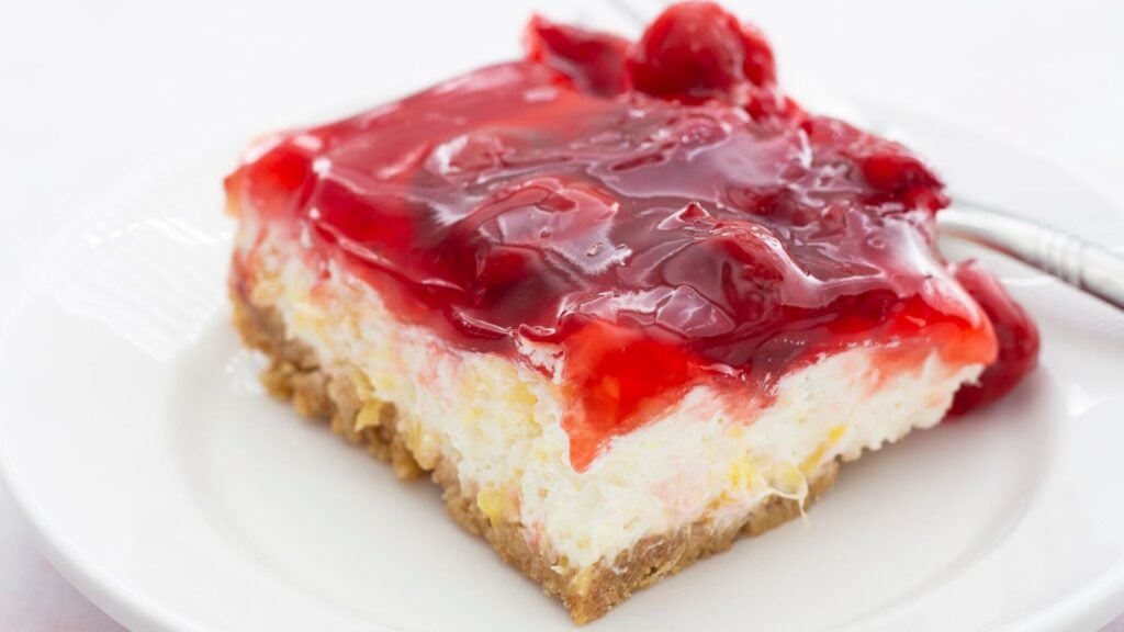 Slice of creamy, cherry topped dessert.