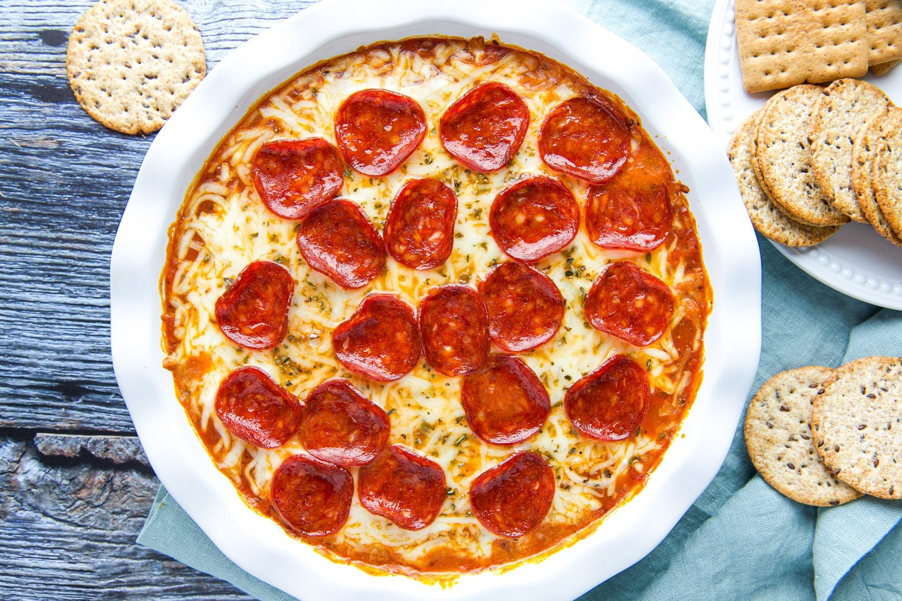 A bowl of Pepperoni Pizza Dip with crackers on the side.