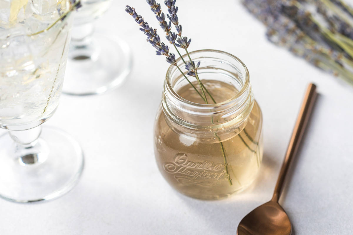 A jar of Lavender Simple Syrup with lavender flowers garnished on top.