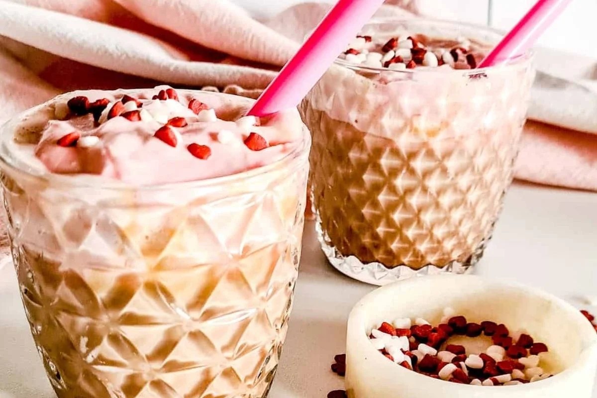 Two glasses of Red Velvet Latters with whipped cream and sprinkles on top.