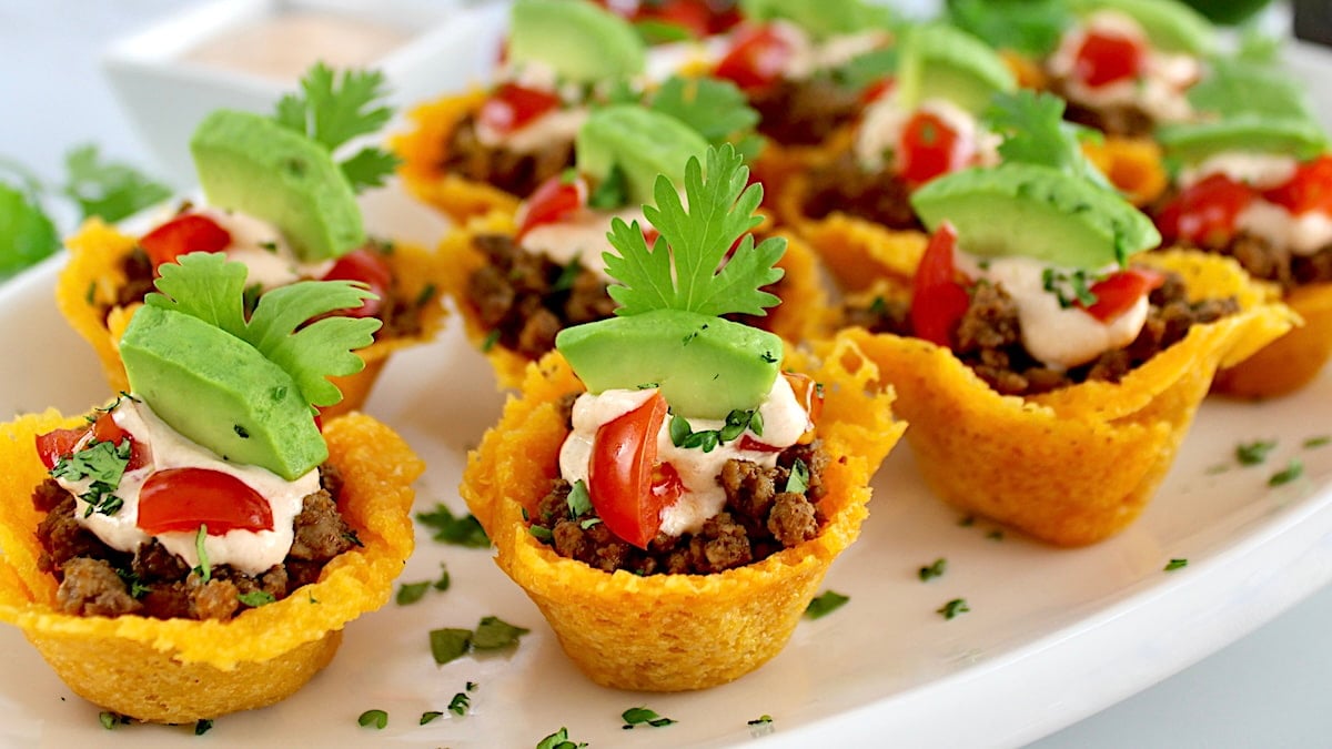 Mini taco bites topped with tomatoes and avocado.