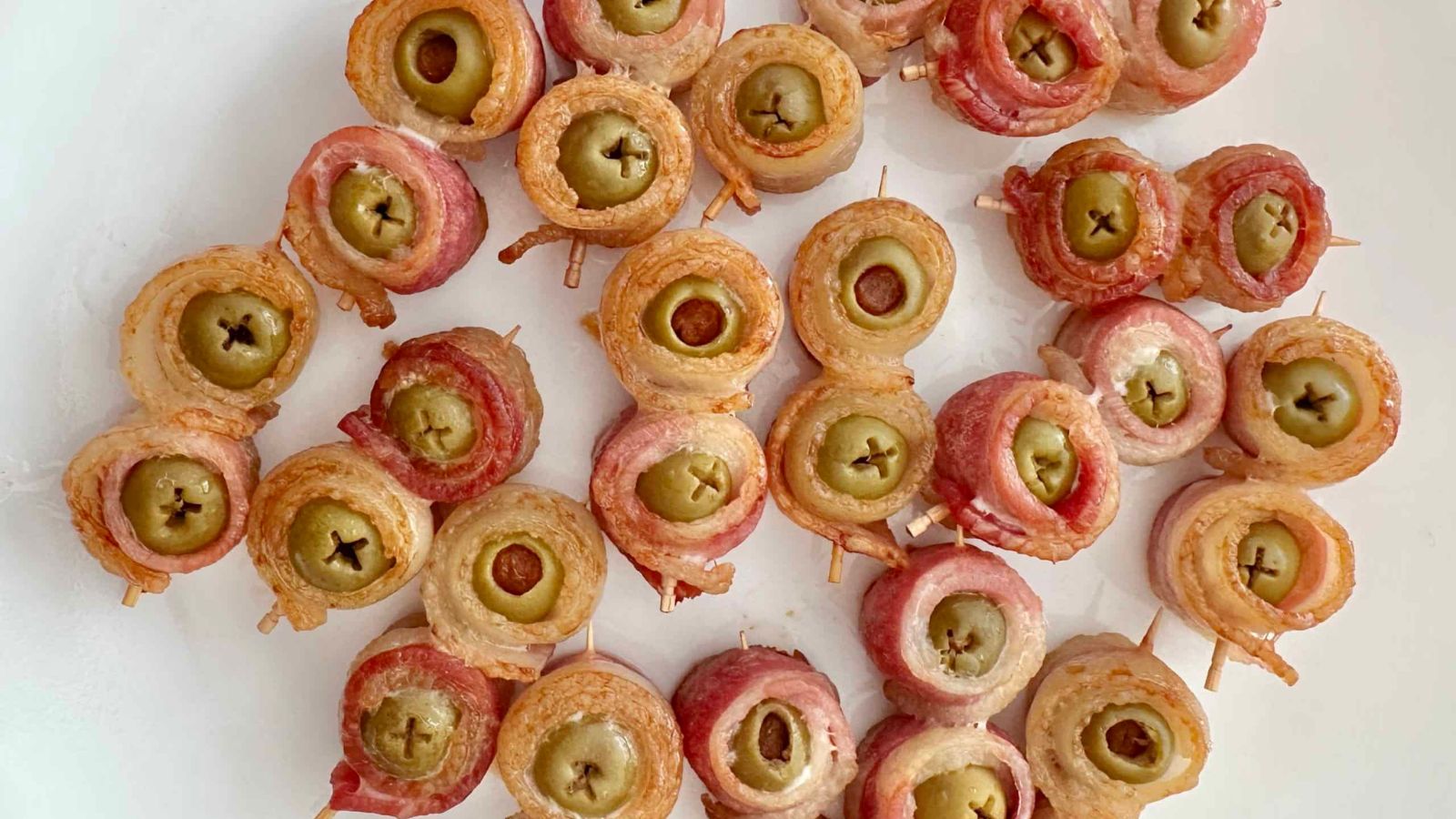 Bacon wrapped olives on a white background.