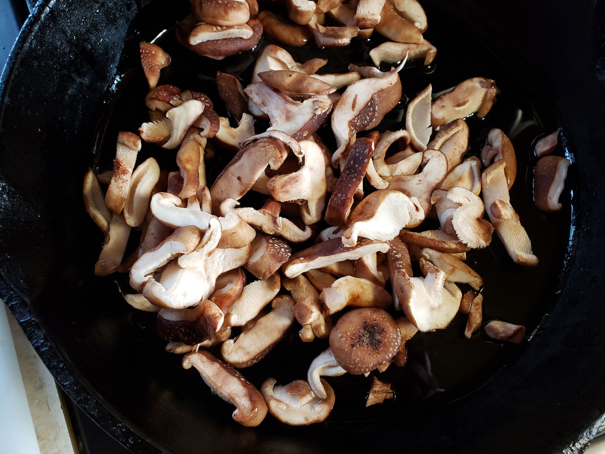 Musrooms sautéing in a cast iron pan.