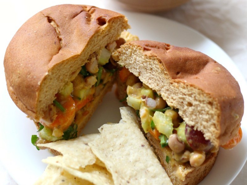 A plate of Curried Black Eyed Pea Salad Sandwiches with chips on the side.