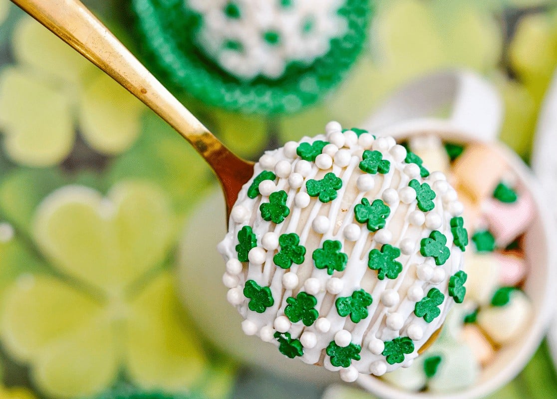 An overhead shot of a spoon holding a St. Patrick's Day Hot Cocoa Bomb