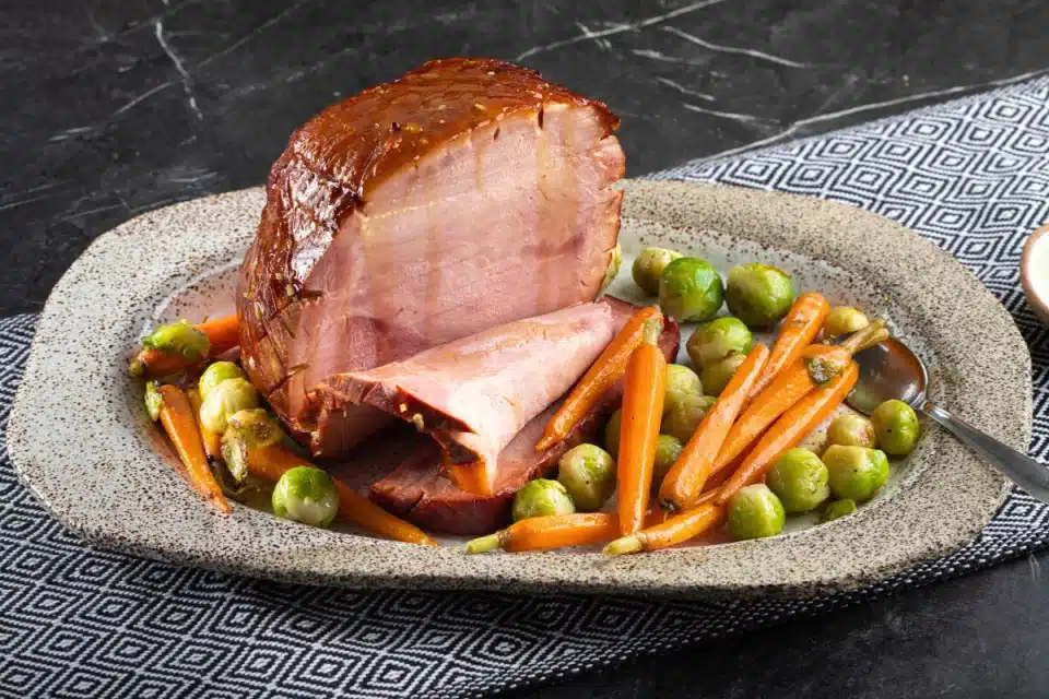 A plate of Garlic-Cinnamon Honey Glazed Ham with Peas and Carrots