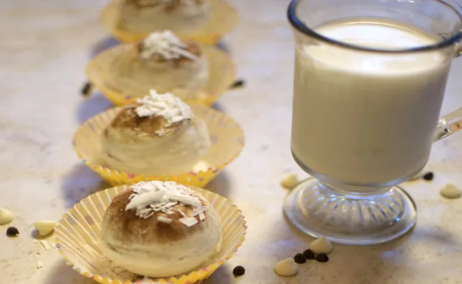 Pumpkin Spice White Chocolate Bombs lined up with a glass of milk on the side.