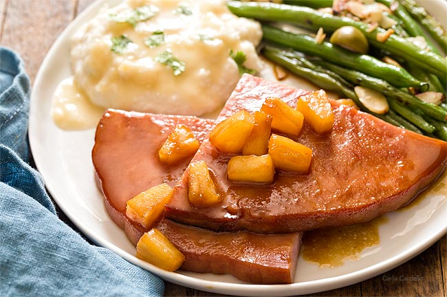 A plate of Honey Glazed Steak Ham with asparagus and mashed potatoes on the side.
