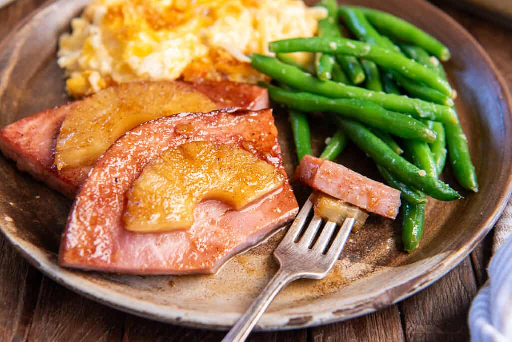 A plate filled with Pineapple Ham Steaks, Green Beans, and Hash Brown.