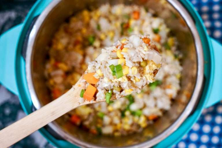 An overhead shot of a spoonful of Vegetable Fried Rice over an instant pot.