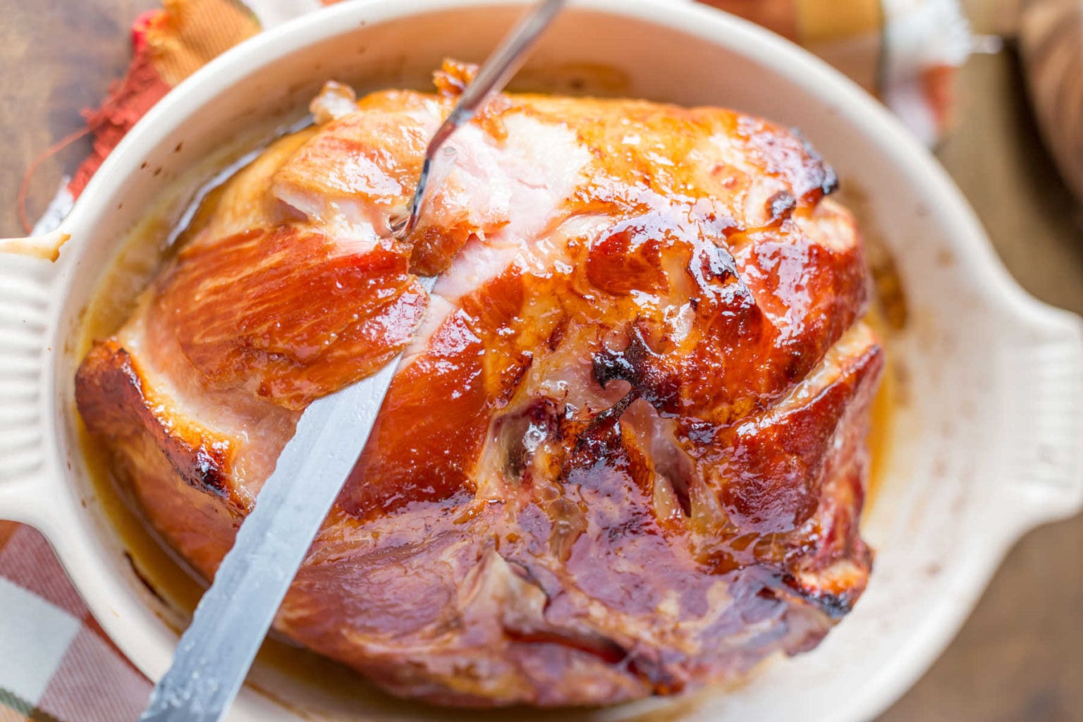 A fork and knife cutting through Maple Glazed Ham