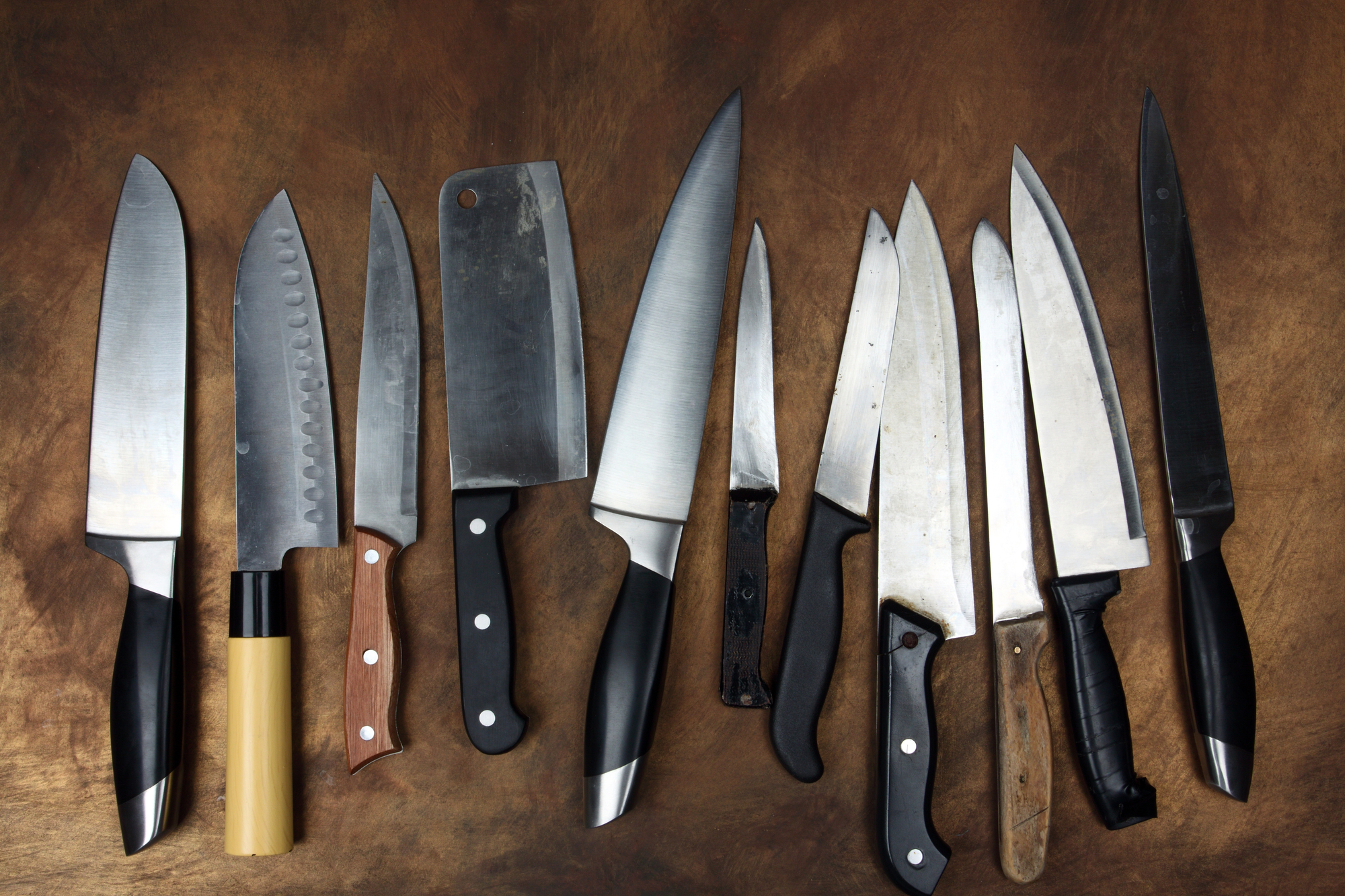 Various Kitchen knives on a wooden board.