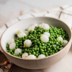 Beige bowl with peas and pearl onions.