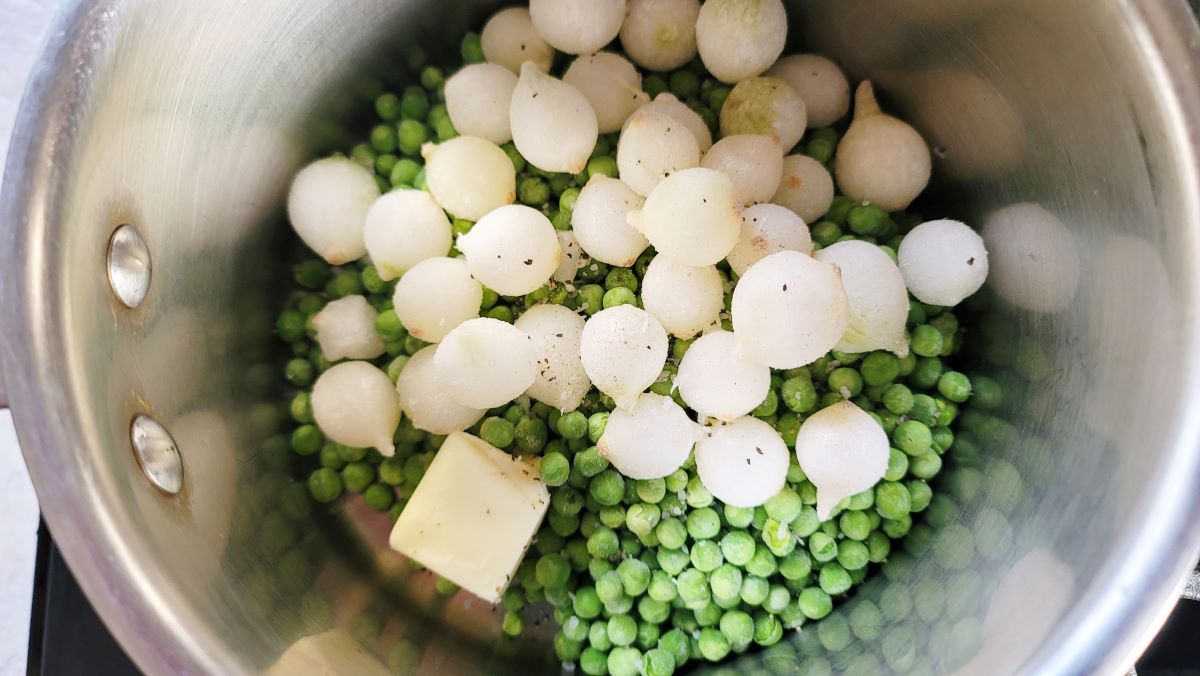 Butter peas and onions in a saucepan.