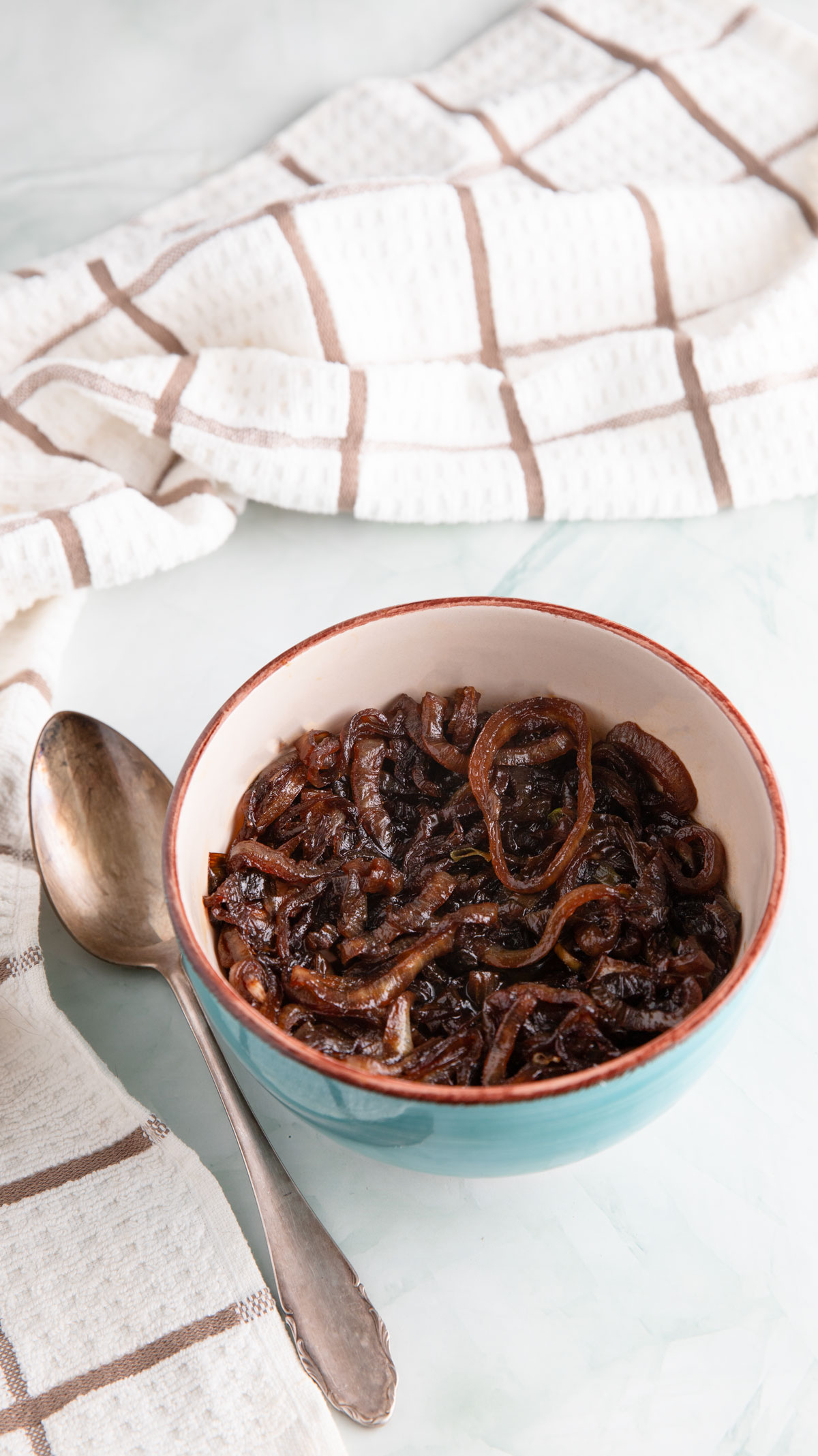 Deep brown caramelized onions in a green bowl.