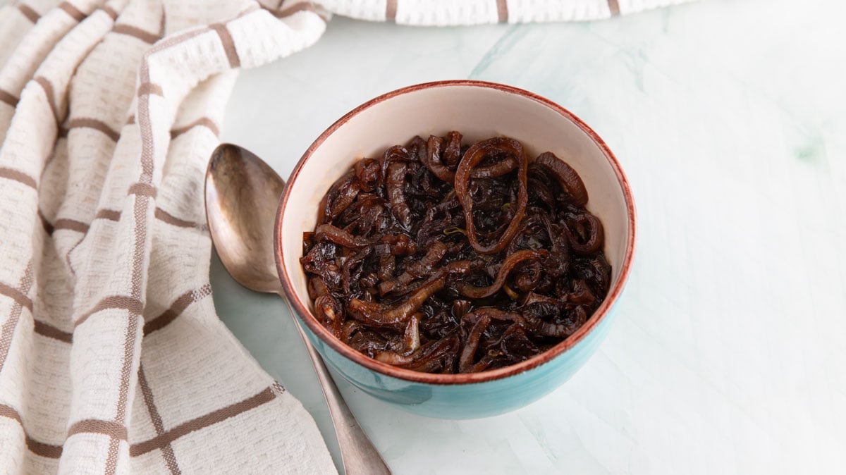 Caramelized onions in a green bowl with a brown rim.