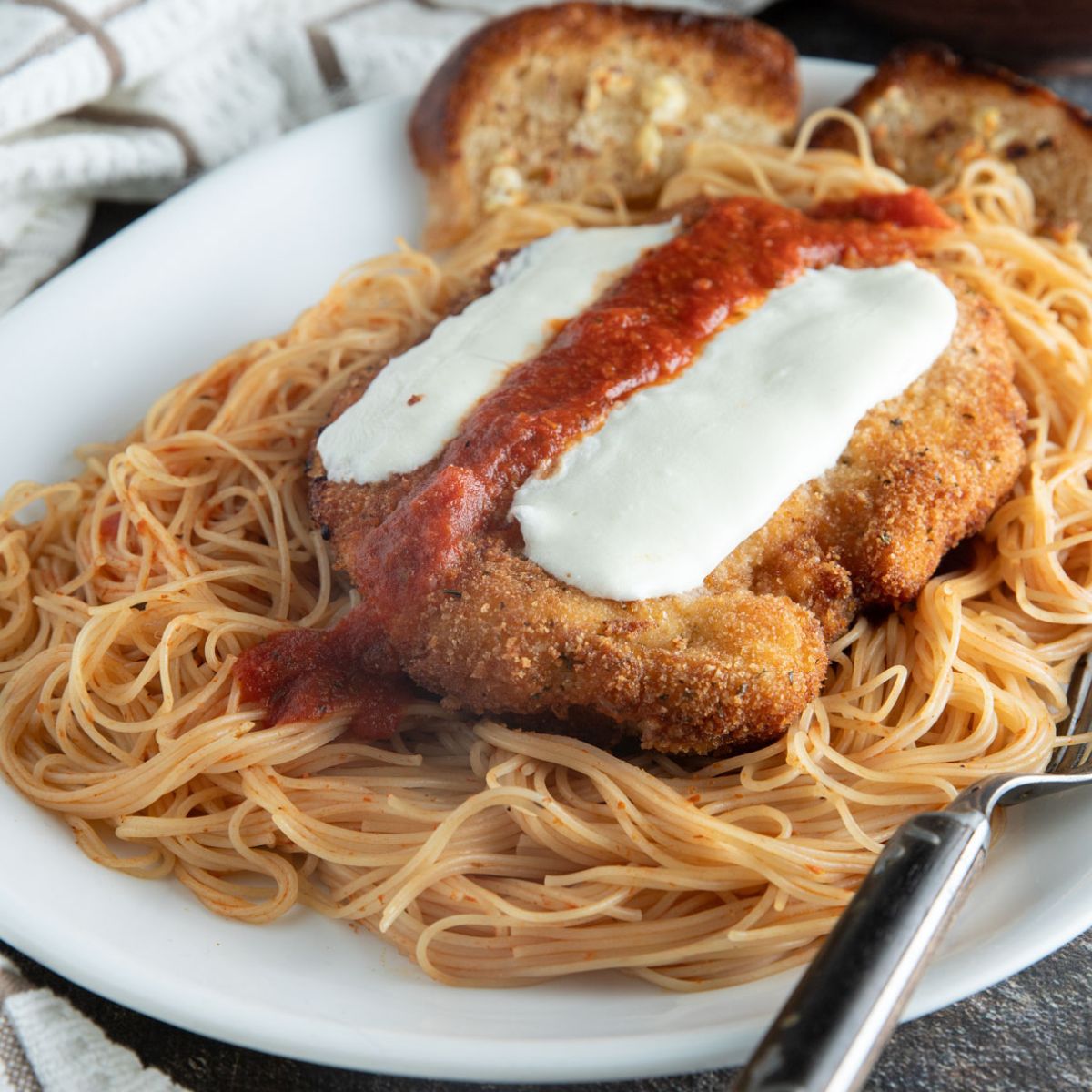 Chicken parmesan on a bed of pasta.