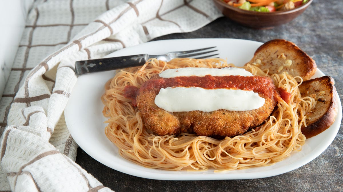 Chicken parmesan on a platter of pasts.
