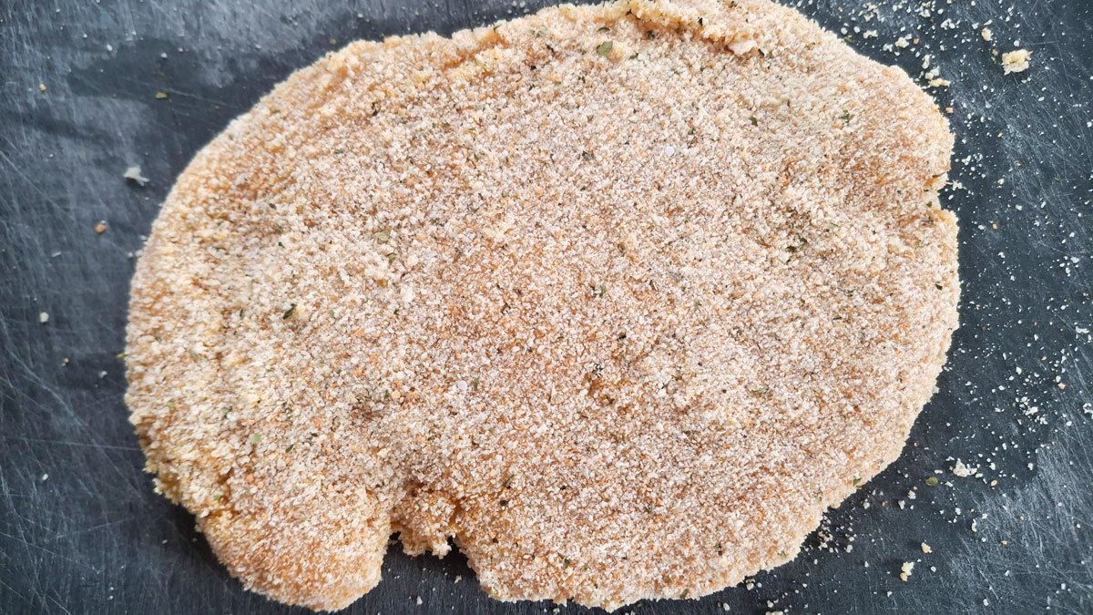 Breaded chicken on a black cutting board.