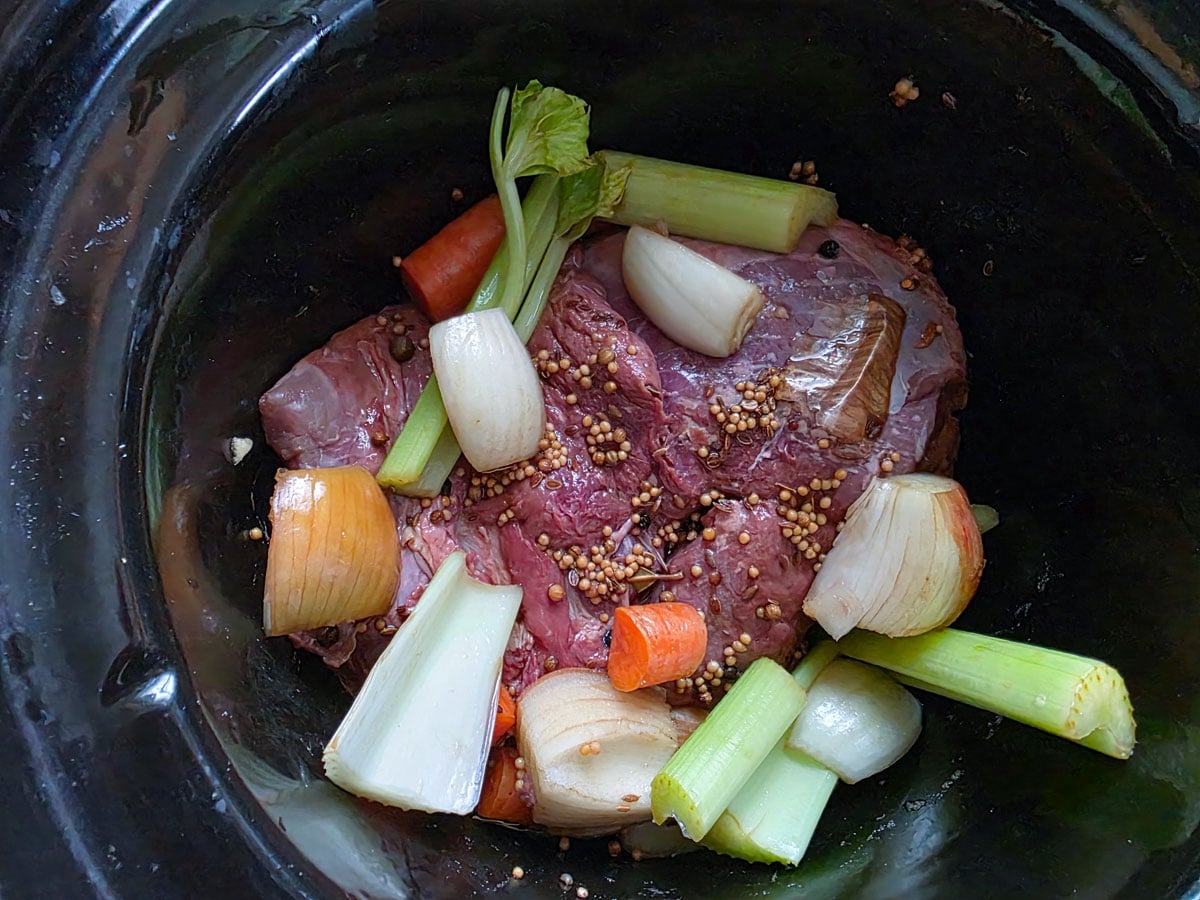 Vension roast in crockpot with vegetables and spices.