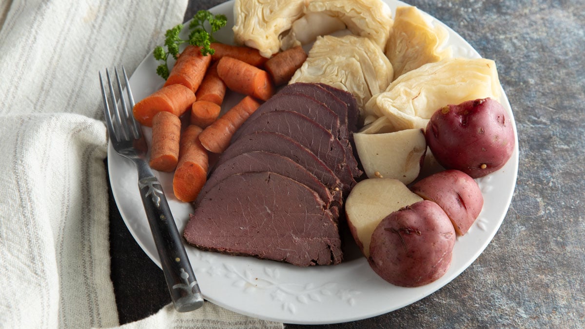 Corned venison and cabbage on a white plate.