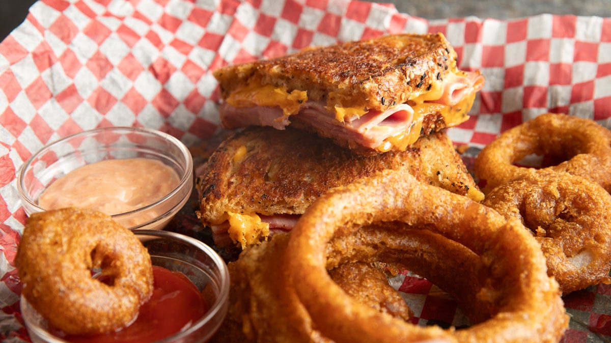 Grilled ham and cheese sandwich with onion rings.