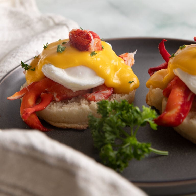 Side view of lobster benedict on a gray plate.