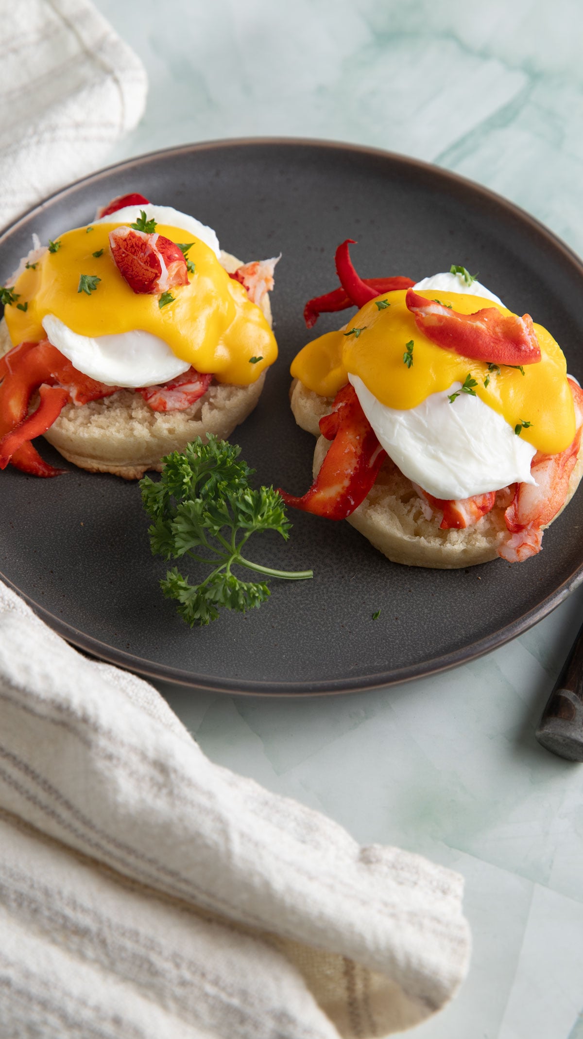 Two halves of lobster benedict with parsley garnish.