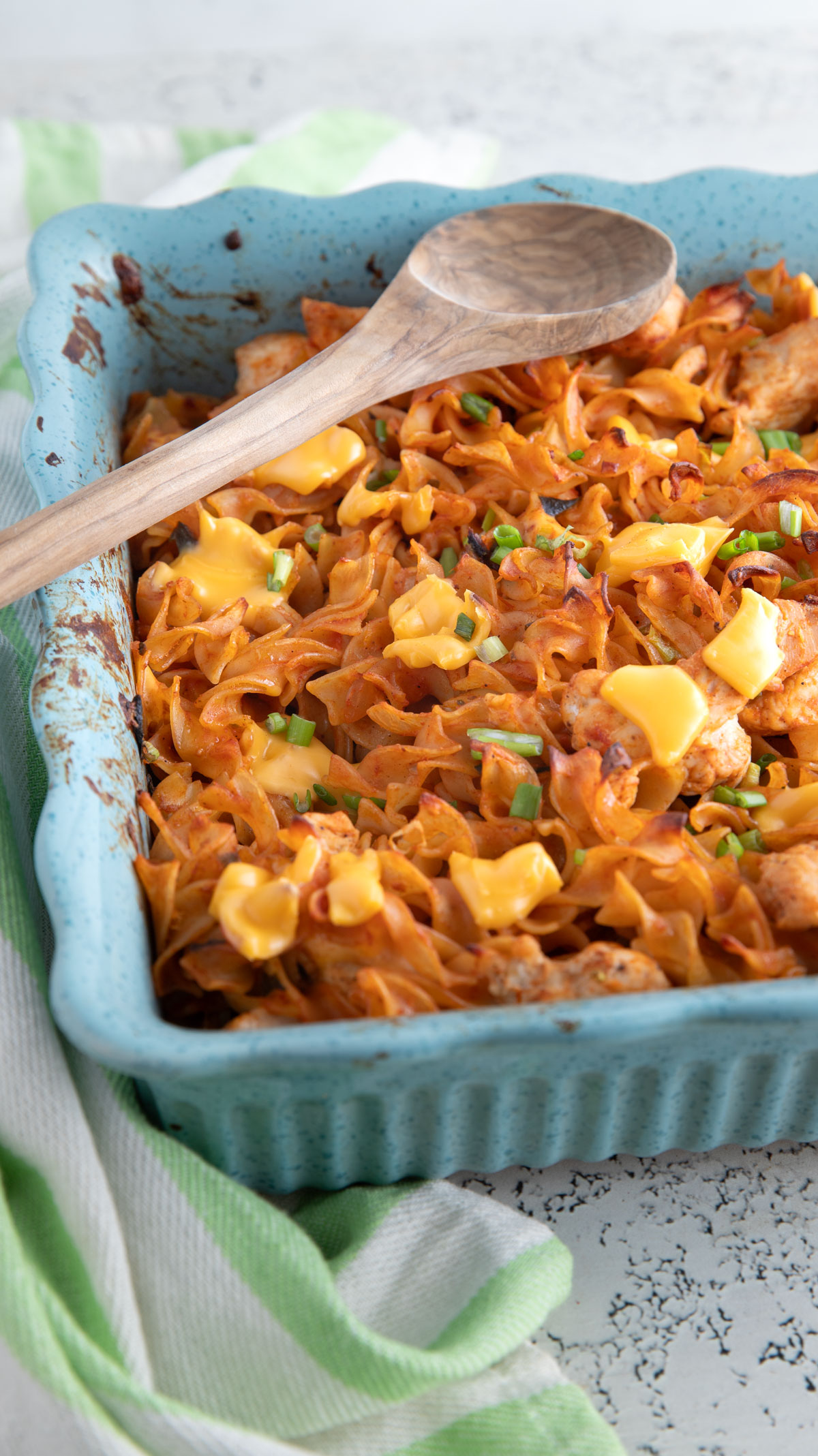 Cheese topped Mexican noodle casserole in a green casserole dish.