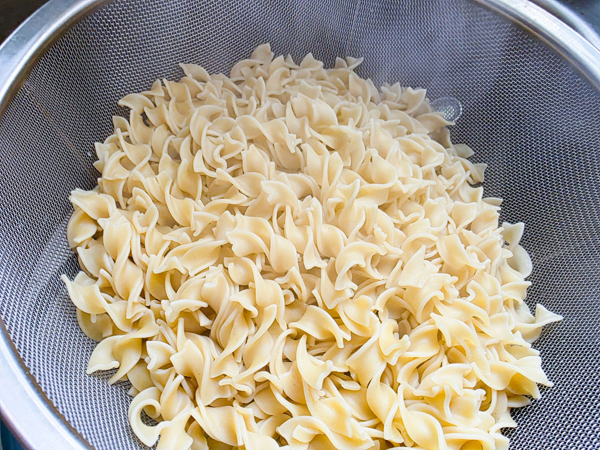 Cooked noodles in a metal colander.